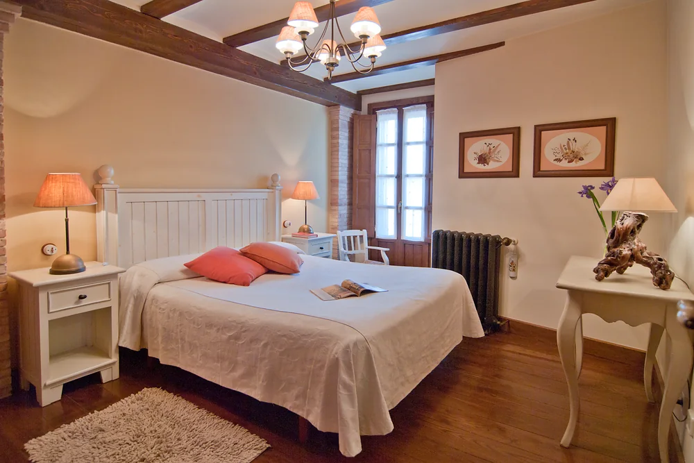 Dormitorio con cama doble y techo de vigas de madera