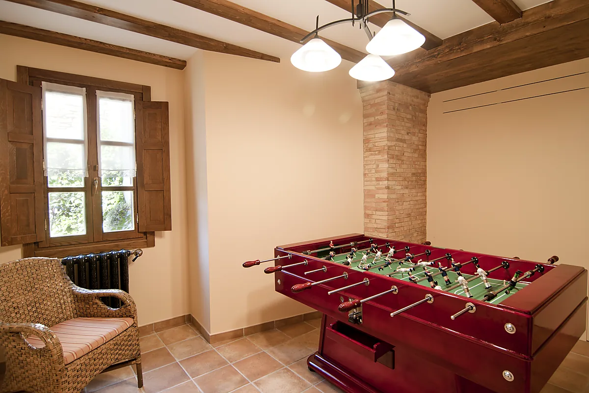 Futbolín en una estancia con ventana y vigas de madera