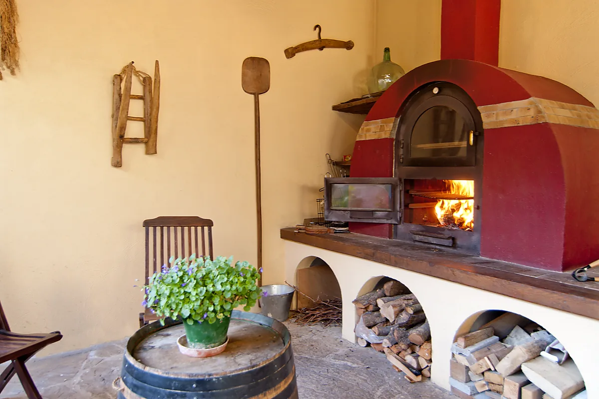 Horno de leña y rincón de descanso en el porche